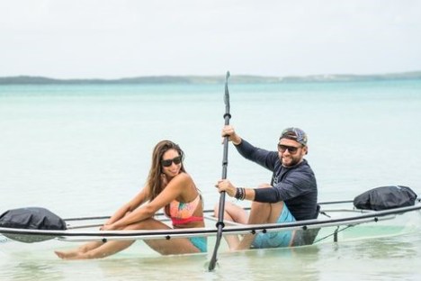 a man and woman sitting next to a body of water